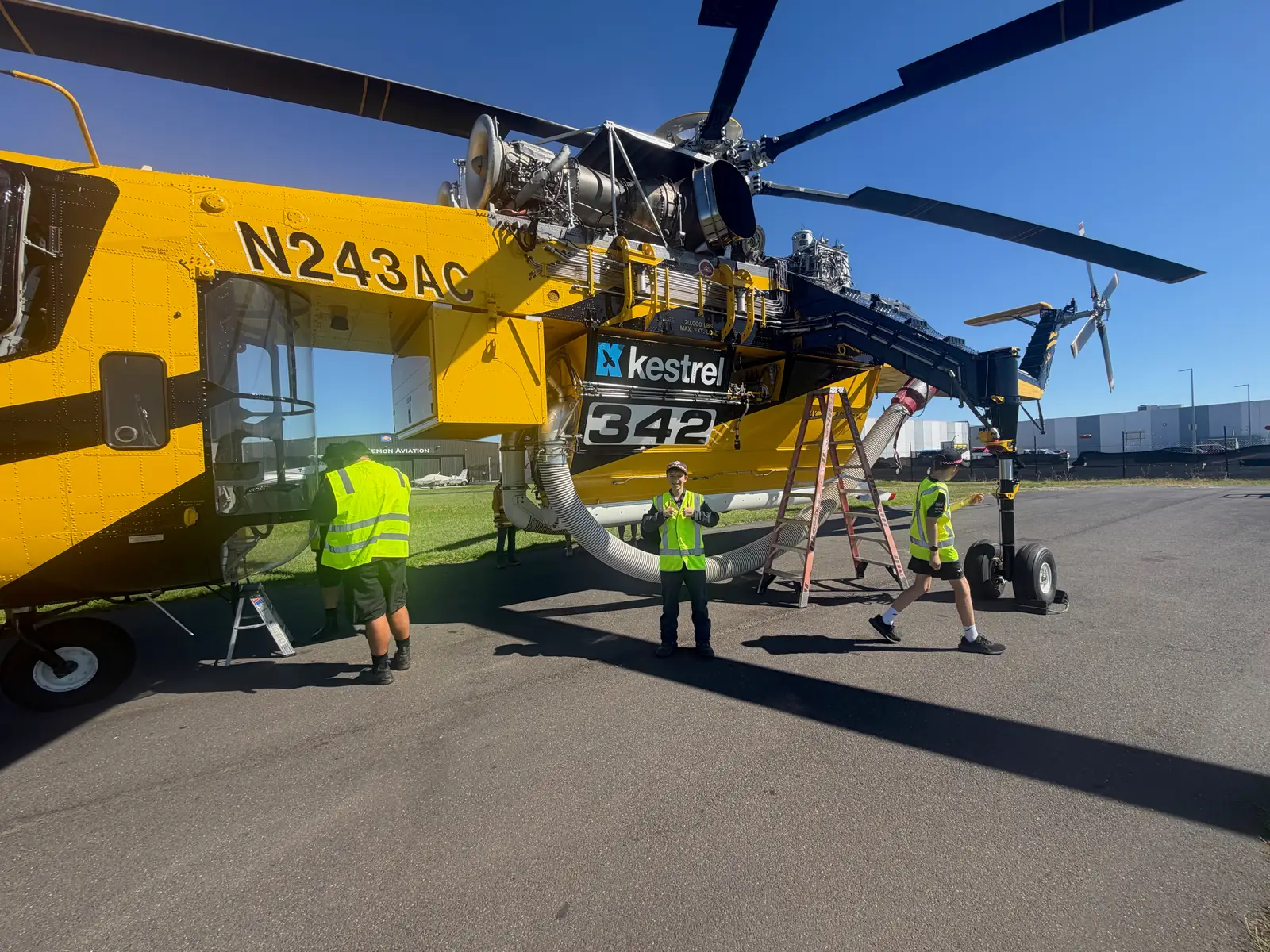 Juniors in high-visibility vests beside the Kestrel Aircrane 342 firefighting helicopter